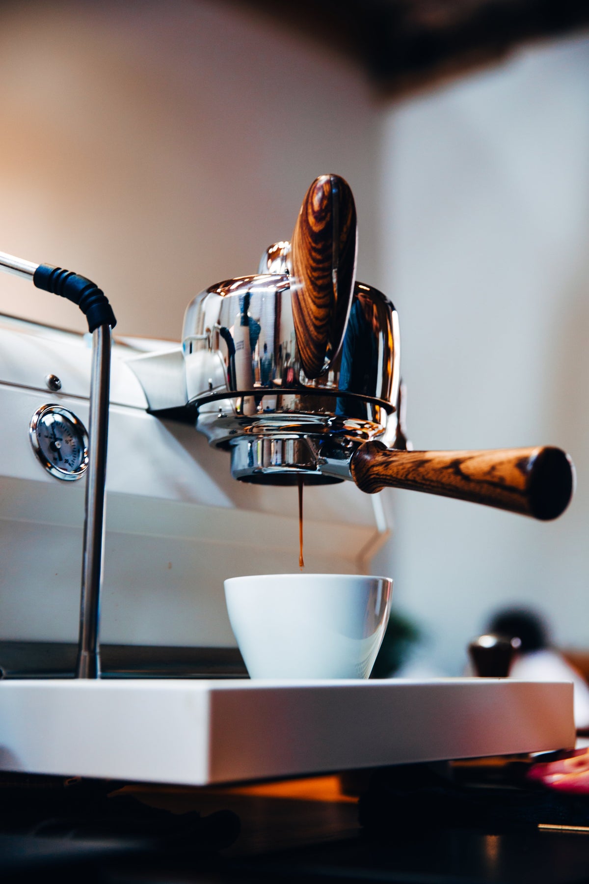 moderne weiße Espressomschine mit Holzgriffen, Esrpesso wird extrahiert.